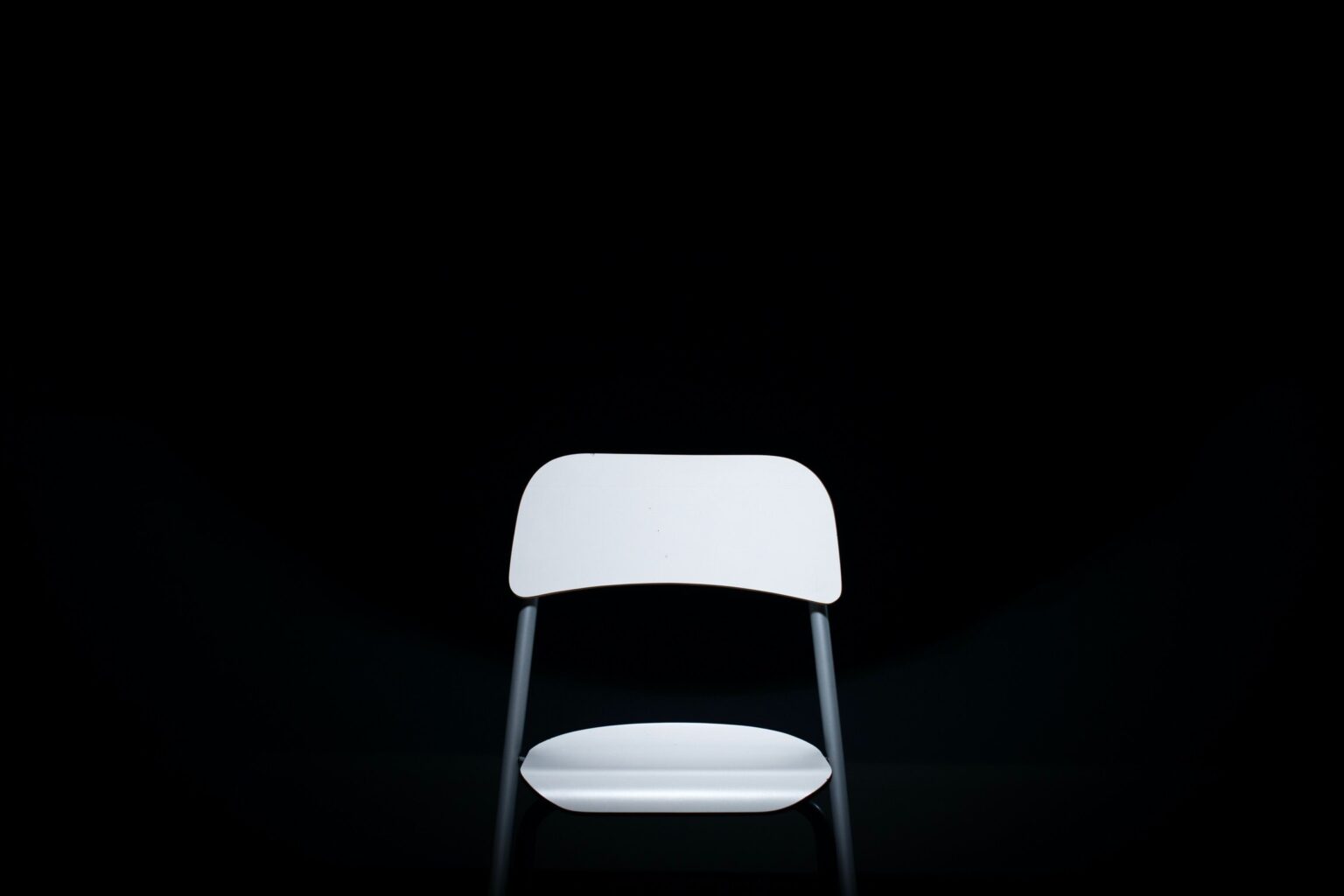 En tom stol står midt i et mørkt rum